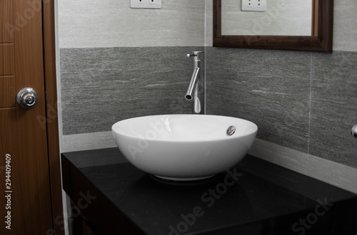 Bathroom interior with white round sink and chrome faucet in a modern bathroom.