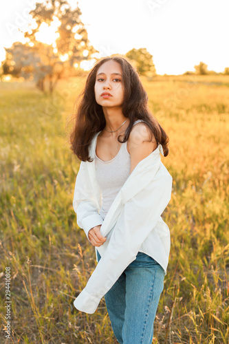 Beautiful young woman in white shirt posing outdoors at sunset