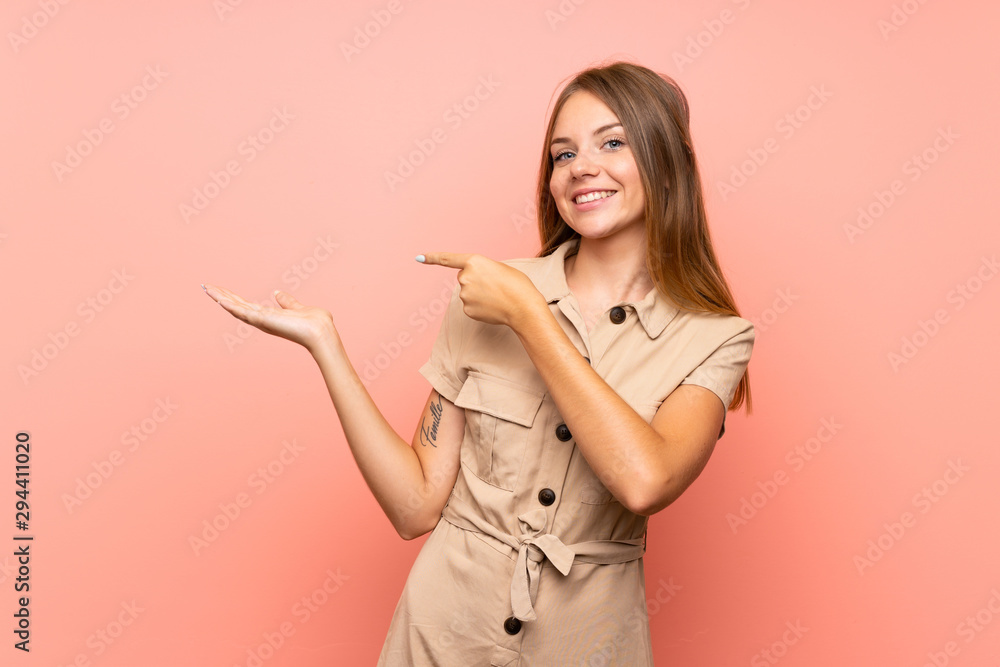Lithuanian blonde girl over isolated pink background holding copyspace imaginary on the palm to insert an ad Lithuanian blonde girl over isolated pink background holding copyspace imaginary on the palm to insert an ad