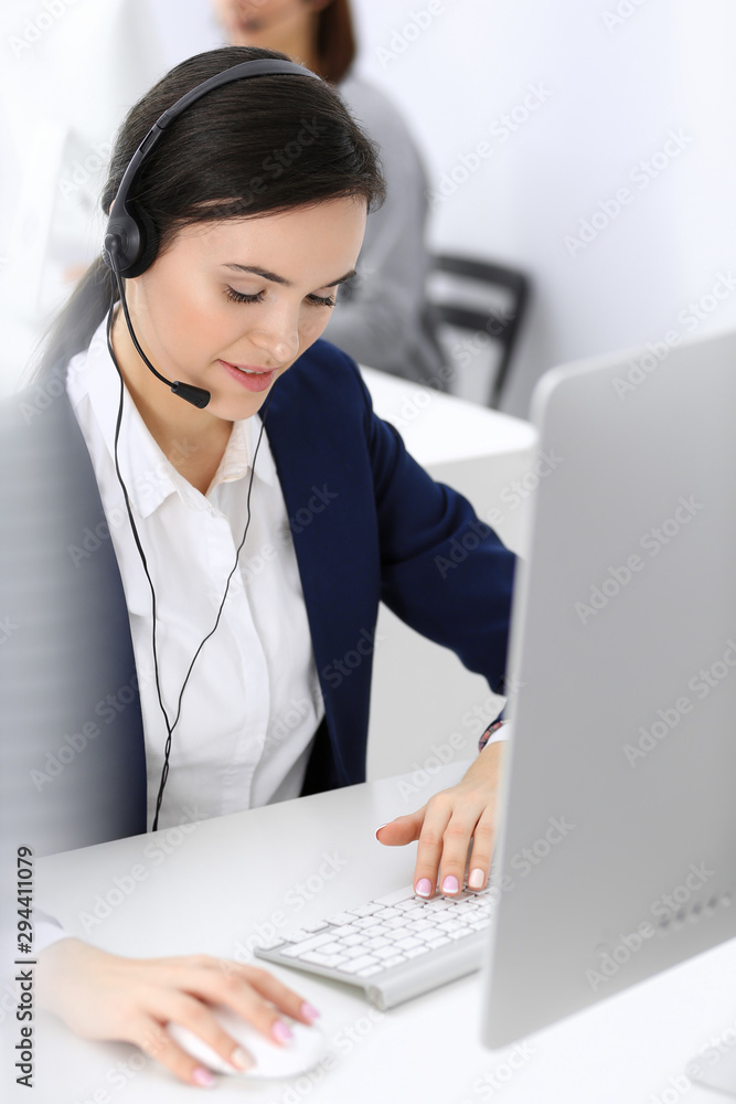 Call center. Beautiful woman receptionist sitting in headset at customer service office. Group of operators at work. Business concept Call center. Beautiful woman receptionist sitting in headset at customer service office. Group of operators at work. Business concept
