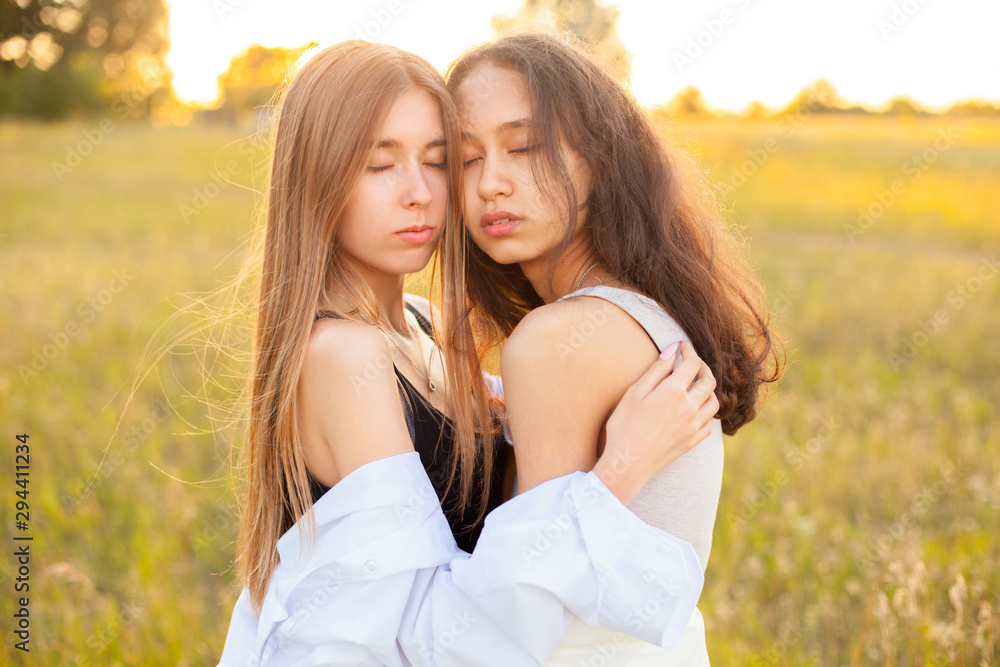 Two young women hugging outdoors at sunset Two young women hugging outdoors at sunset