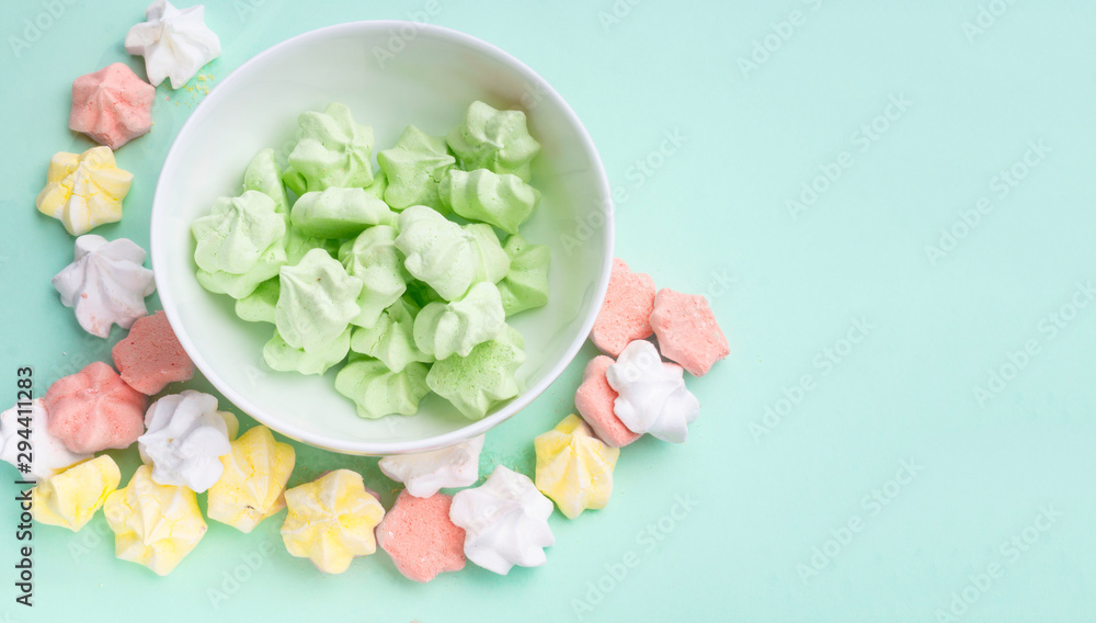 banner of pastel colored merengues cookies on mint green color background top view