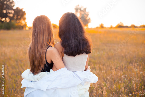 Two young women in white shirts looking on the sunset