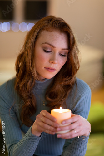 Portrait of millennial woman holding candle at home 