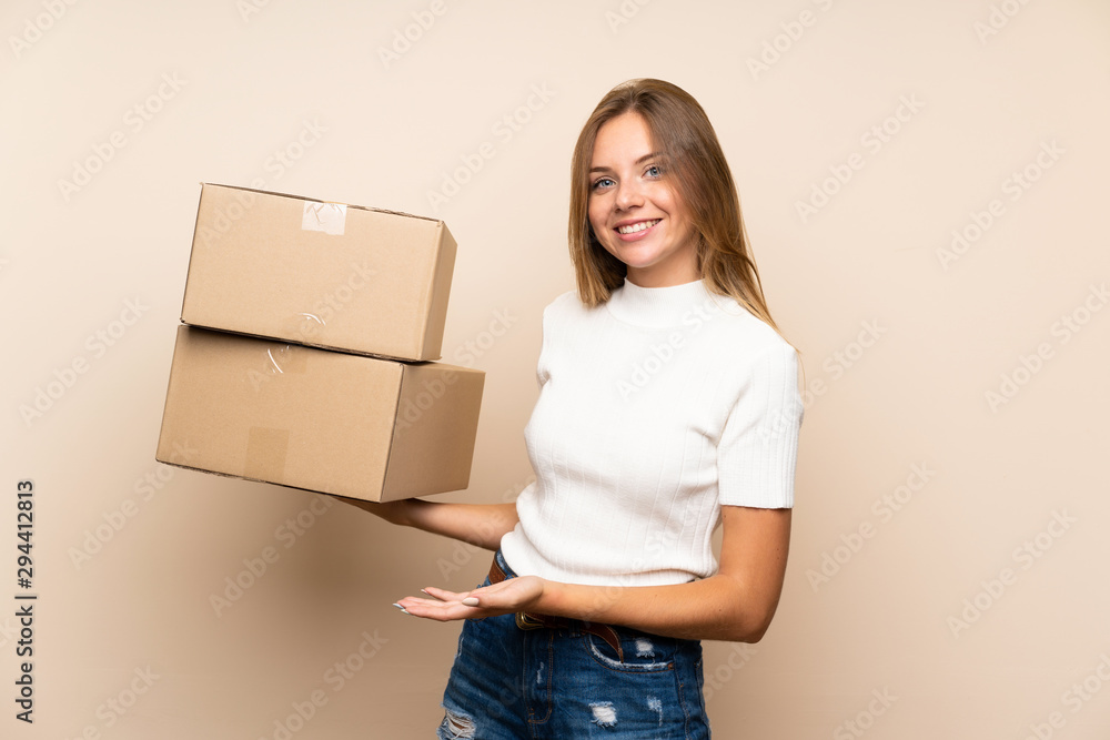 Young blonde woman over isolated background holding a box to move it to another site Young blonde woman over isolated background holding a box to move it to another site