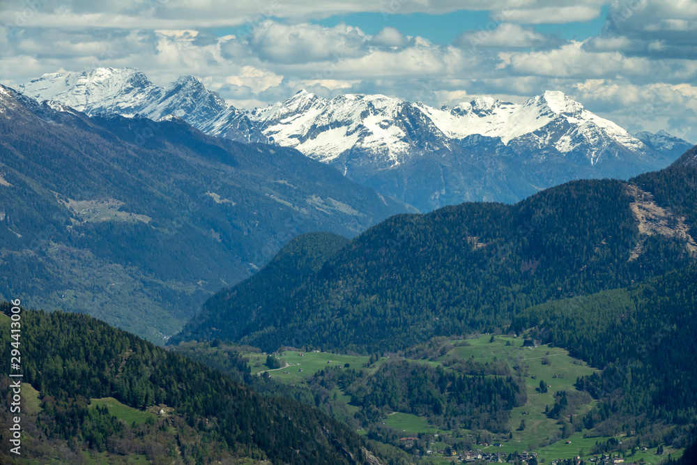 Beautiful aerial view of high snow-covered mountains and valley with village in Switzerland