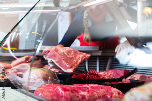 Meat in a butcher shop display being put in by sales woman