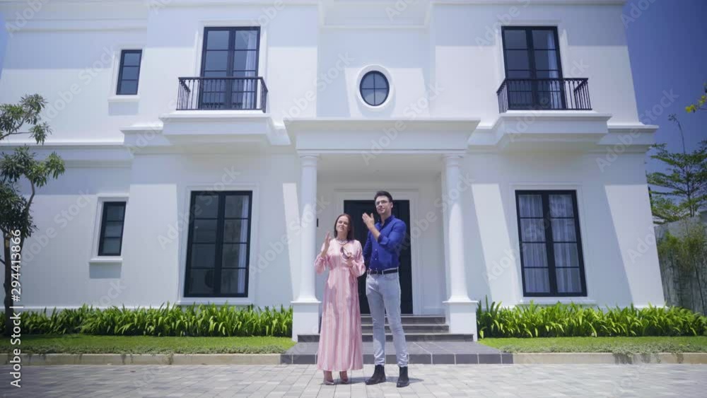 Caucasian couple talking together while standing in front of a new luxury house. Shot in 4k resolution Caucasian couple talking together while standing in front of a new luxury house. Shot in 4k resolution