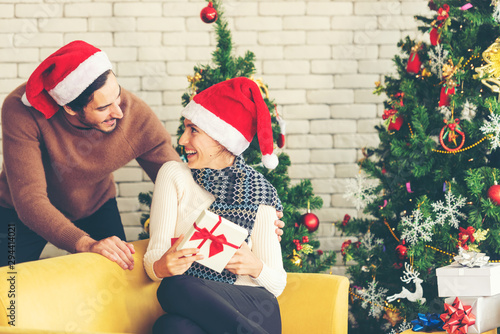 Merry Christmas. Boyfriend surprising his girlfriend with Christmas gift. Young couple celebrating and party and drinking champagne new year and Christmas with present and Christmas tree at home. ..