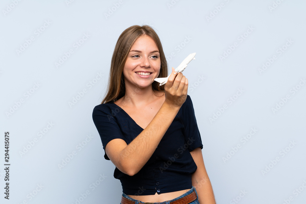Fototapeta premium Young blonde girl holding a toy airplane over isolated background