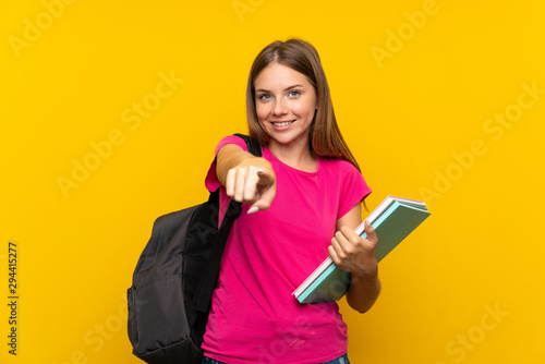 Young student girl over isolated yellow background points finger at you with a confident expression