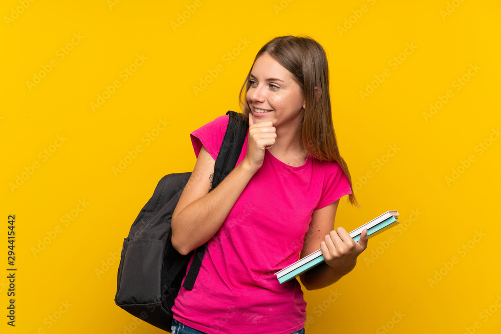 Young student girl over isolated yellow background thinking an idea and looking side Young student girl over isolated yellow background thinking an idea and looking side