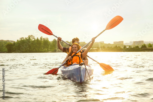 Принти на полотні Happy young caucasian couple kayaking on river with sunset in the backgrounds