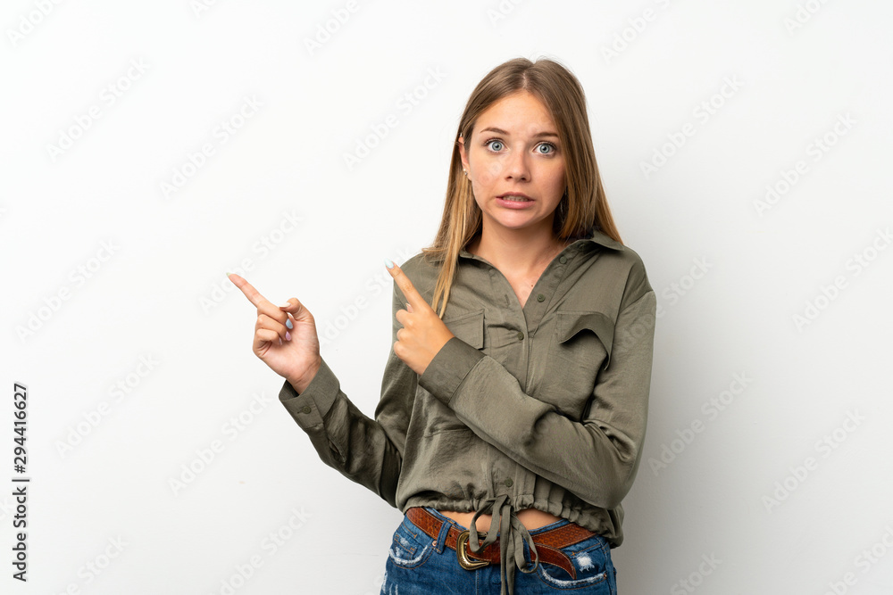 Lithuanian blonde girl over isolated white background frightened and pointing to the side Lithuanian blonde girl over isolated white background frightened and pointing to the side