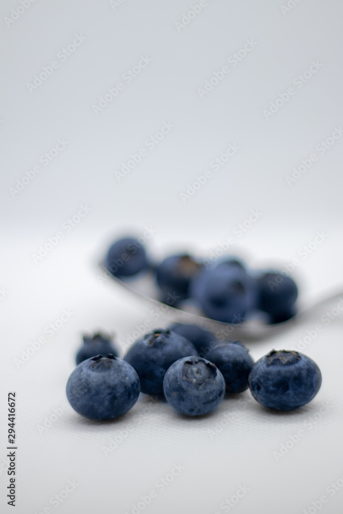 Some fresh and healthy blueberries on top of a spoon with white background