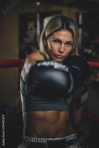 Attractive female boxer is making her strong punch while posing for photographer.