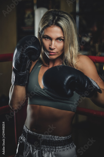 Portrait of experienced female boxer in boxing gloves and activewear.