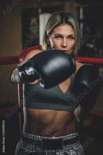 Focused muscular woman has her boxing training wearing boxing gloves.