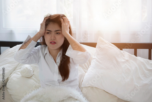 Asian young woman sitting in bed with tired after sleepless . .Lady stressed because of too early wakeup, Woman suffering from lack of sleep.