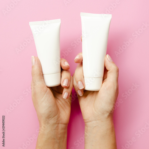 Close-up hands holding cream bottles