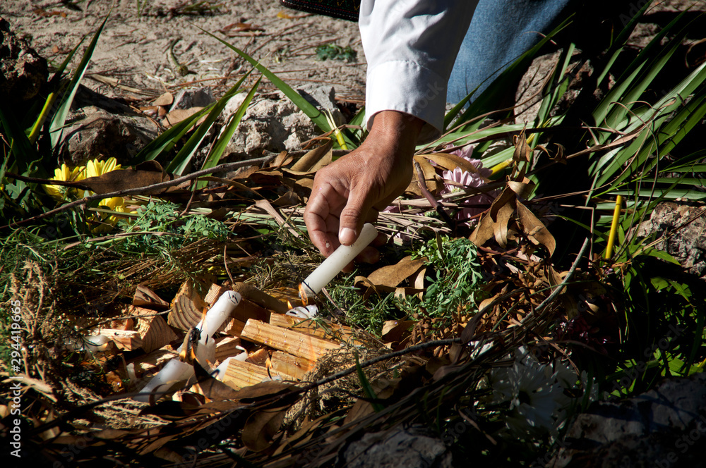 Obraz premium A mayan priest is lighting fire with candles in ceremonial fire ritual, flowers and herbs can be seen.