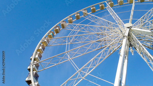 White Big wheel spinning at an Amusement park with blue sky in the background