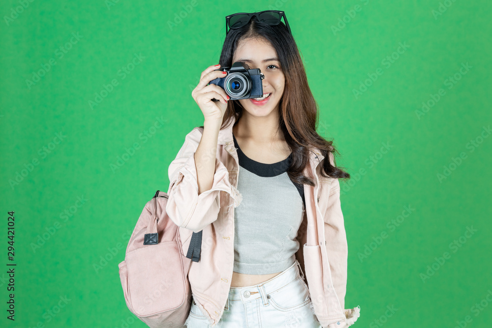 Cheerful young Asian woman with bag and digital camera ready enjoy travel over green isolated background. Cheerful young Asian woman with bag and digital camera ready enjoy travel over green isolated background.