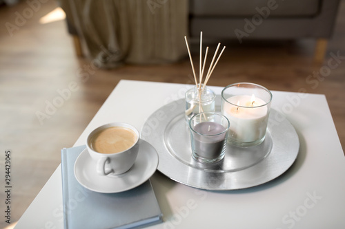 Fototapeta Naklejka Na Ścianę i Meble -  hygge and aromatherapy concept - coffee, candles, book and aroma reed diffuser on table at home