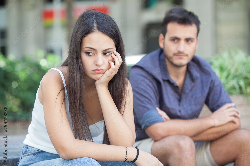 Sad young couple sitting on the bench after a quarrel. Breakup concept Sad young couple sitting on the bench after a quarrel. Breakup concept