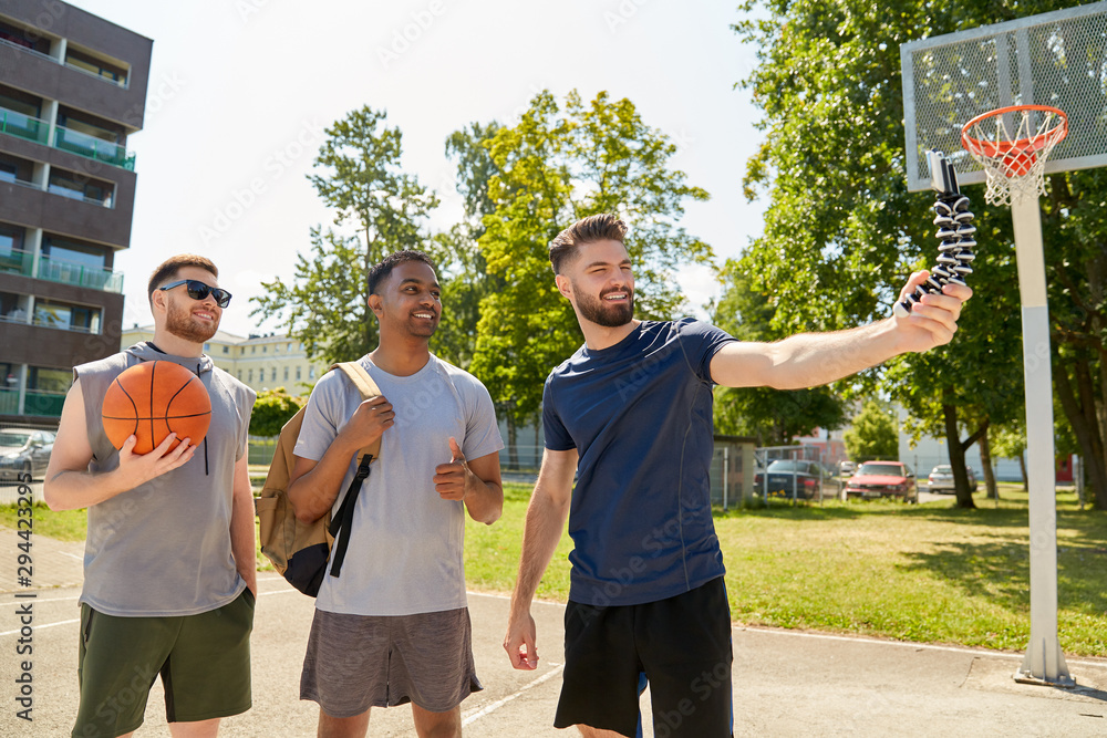 sport, leisure games and male friendship concept - group of happy men or  friends taking selfie by smartphone on tripod on outdoor basketball  playground foto de Stock | Adobe Stock