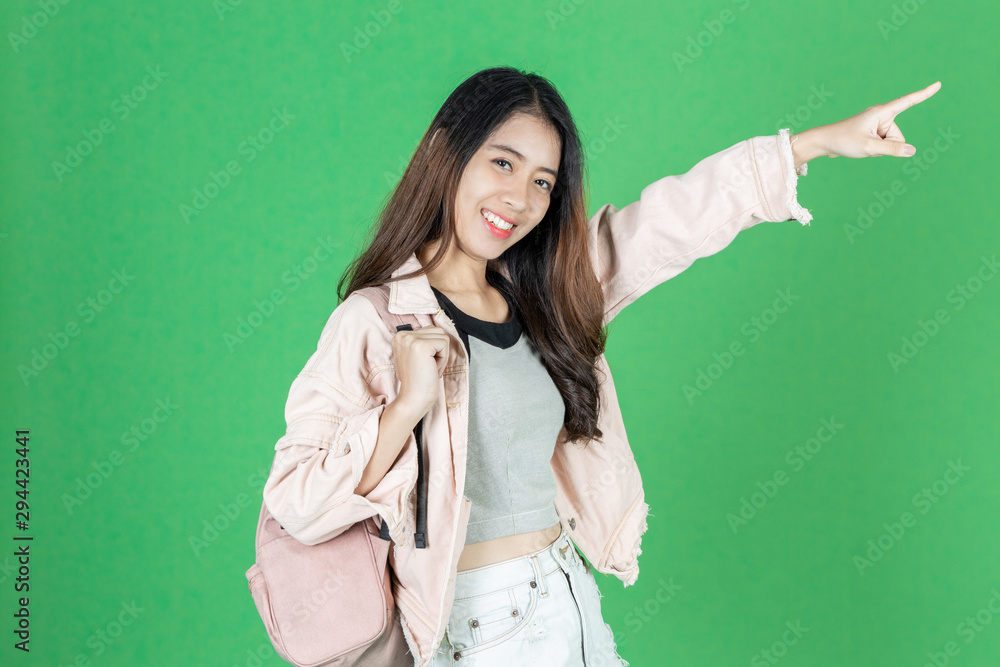 Attractive young Asian tourist girl with bag ready to travel over green isolated background. Attractive young Asian tourist girl with bag ready to travel over green isolated background.