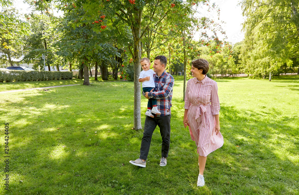 Fototapeta premium family, leisure and people concept - happy mother, father and little son at summer park