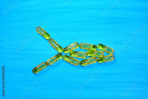 Fish oil capsules arranged in a fish shape on a blue wooden background