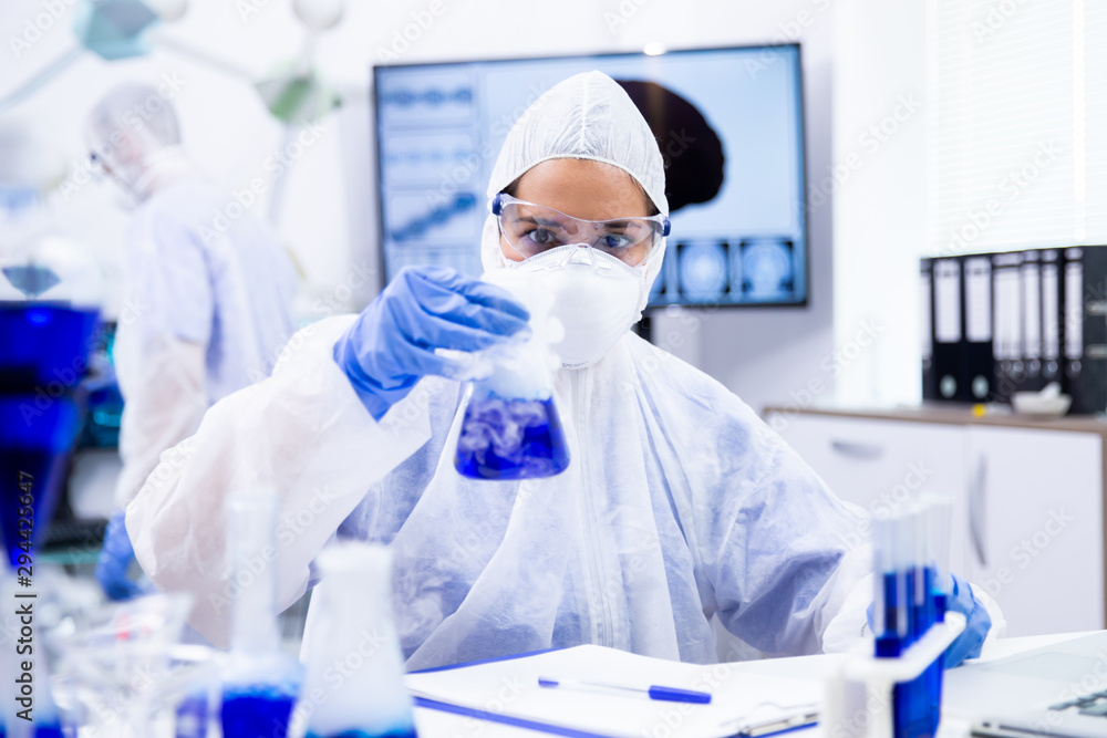 Researcher in protective suit holding a container from which comes a white smoke Researcher in protective suit holding a container from which comes a white smoke