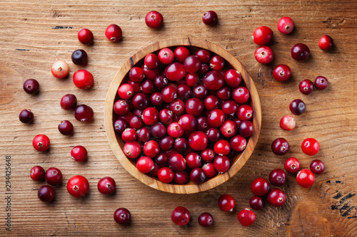 Ripe fresh cranberry in wooden bowl on rustic table top view. photo