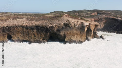 Ocean waves hitting the cliffs near Praia de Monte Clérigo in Portugal