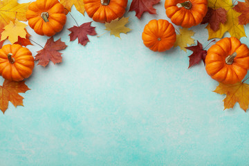 Autumn Thanksgiving background. Pumpkins and maple leaves on turquoise table top view.