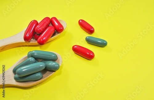 B vitamins and zinc capsules in a wooden spoon on a yellow background