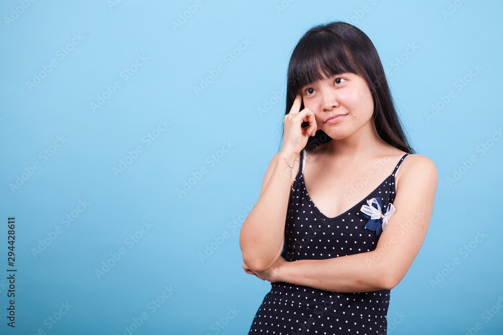 Portrait of thoughtful asian girl in studio over blue background Portrait of thoughtful asian girl in studio over blue background