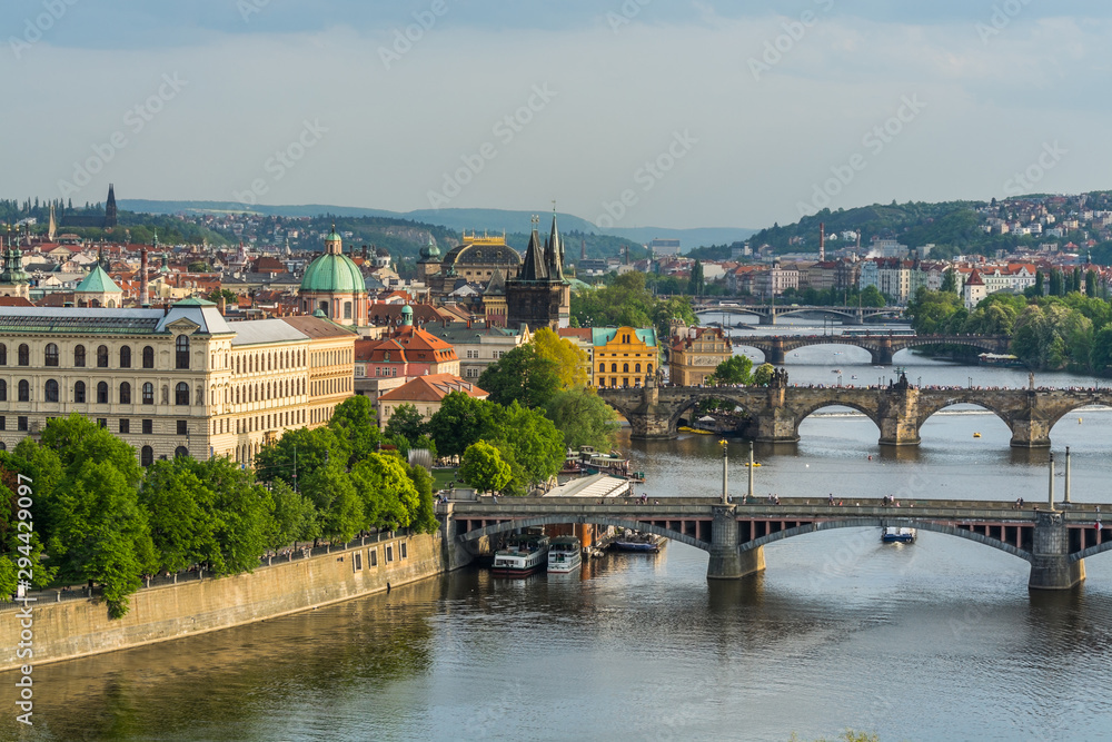 Aerial view of citycape of old town of Prague, with a lot of  rooftops, churches, and the landmark of Charles Bridge, and Vltava river.