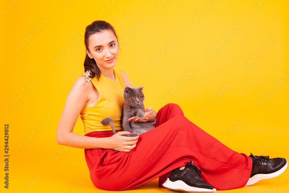 Obraz premium Beautiful girl smiling while holding her adorable cat