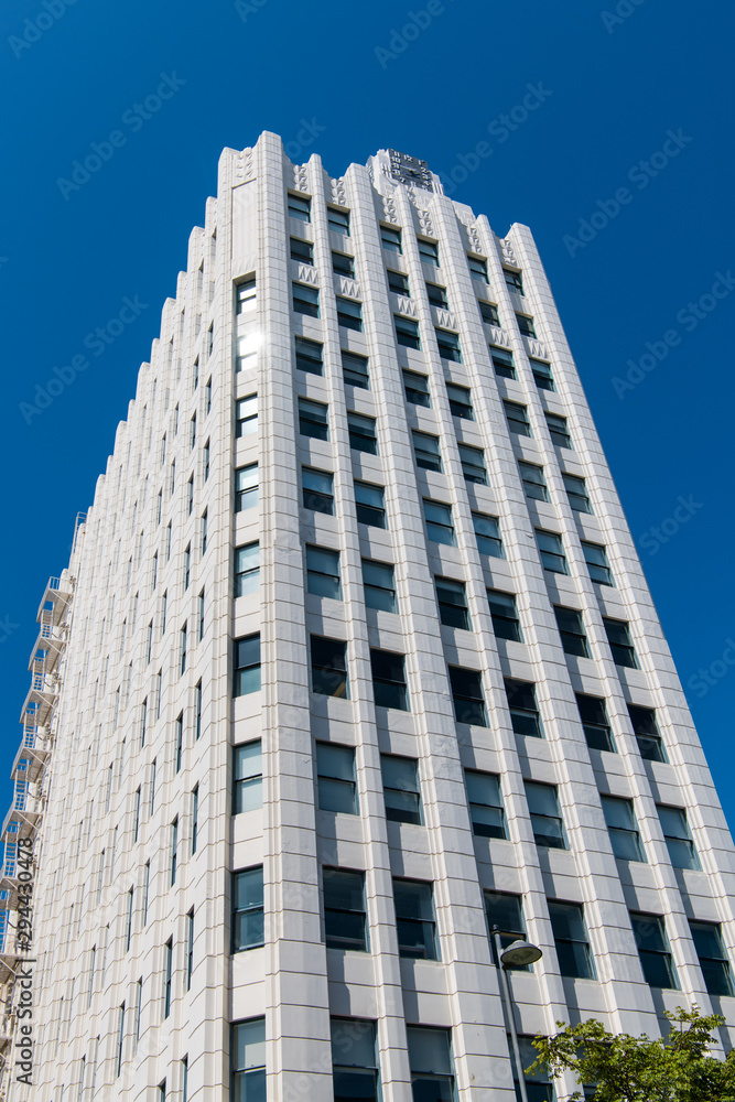 Vertical view of a beautiful art deco style skyscraper clad in white stone with a clock on top