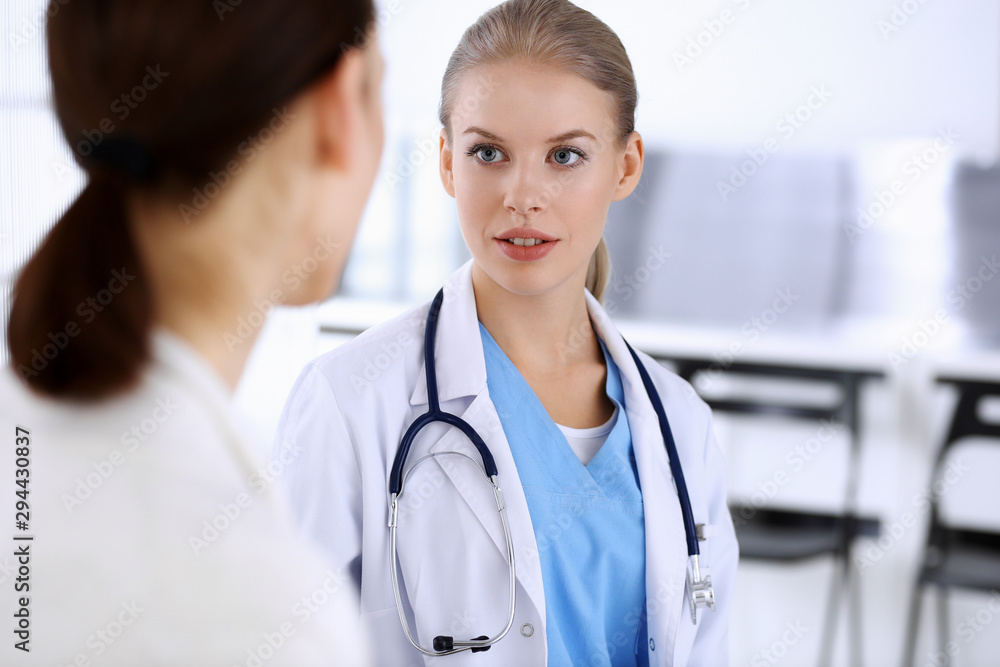Doctor and patient during consultation. Physician at work filling up medication history record while sitting in emergency hospital, portrait shoot. Medicine and health care concept Doctor and patient during consultation. Physician at work filling up medication history record while sitting in emergency hospital, portrait shoot. Medicine and health care concept