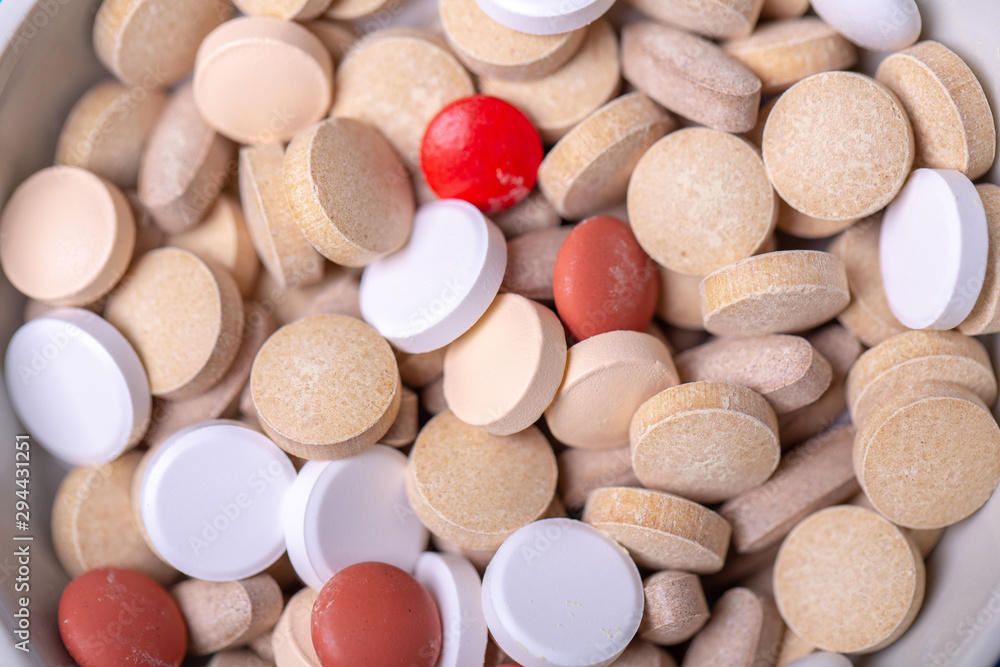 Close up with a red pill among several pills of different colors Close up with a red pill among several pills of different colors