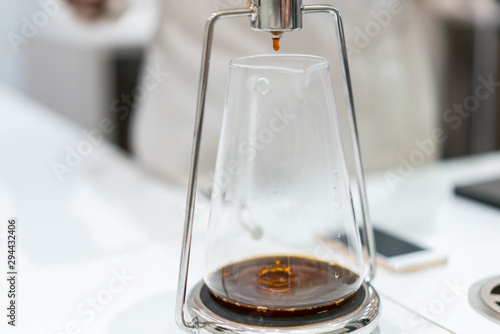 process of preparation black coffee in chemex pour over coffee maker in bright modern cafe. Alternative ways of brewing coffee. photo