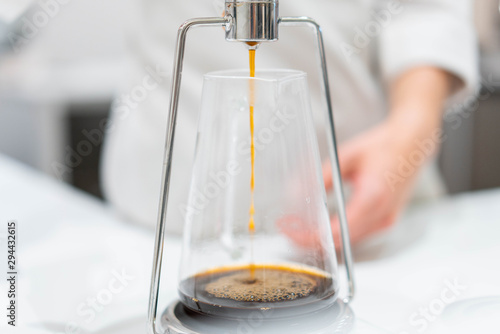 process of preparation black coffee in chemex pour over coffee maker in bright modern cafe. Alternative ways of brewing coffee. photo