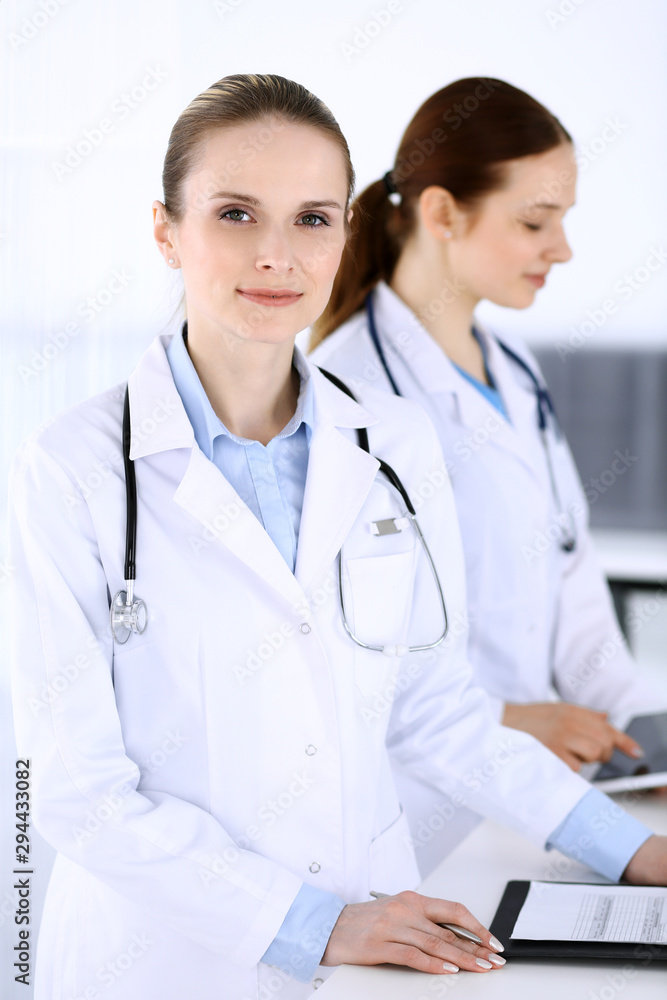 Group of doctors at work in hospital. Physician filling up medical documents or prescription while standing at reception desk. Data in medicine and health care concept Group of doctors at work in hospital. Physician filling up medical documents or prescription while standing at reception desk. Data in medicine and health care concept