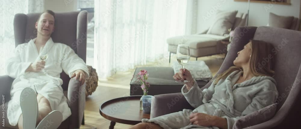 a couple sitting in armchairs in the lounge of a spa having conversation and drinking wine - Ein Paar sitzt in Sesseln der Lounge eines Spas, unterhalten sich und trinken Wein 4K ProRes Footage