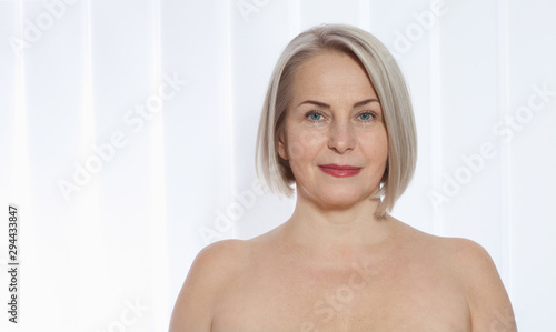 Portrait of cheerful senior woman smiling while looking away at spa. Happy mature woman after spa massage and anti-aging treatment on face. Realistic images with their own imperfections.