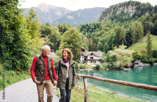 Fotografie A senior pensioner couple hiking in nature, holding hands.